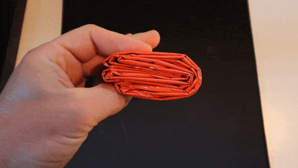 Shown how compact the emergency survival jacket is by folding it into wallet size