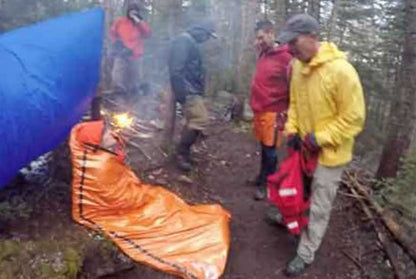 emergency sleeping bag worn by a man in the woods while camping